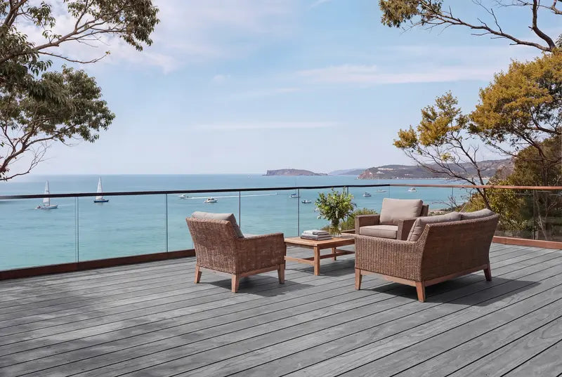Outdoor deck with wicker chairs and table overlooking a scenic ocean view.