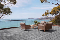 Outdoor deck with wicker chairs and table overlooking a scenic ocean view.